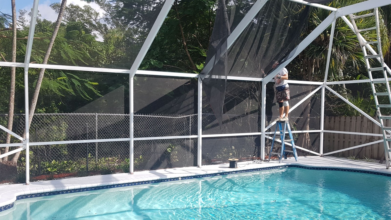 Technician replacing pool cage screen panels